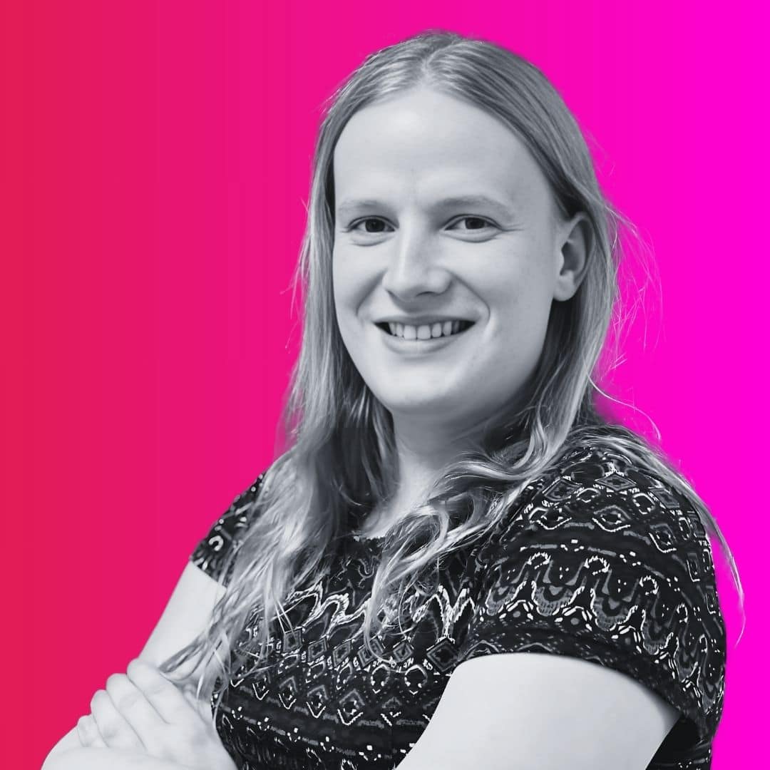 Frau lächelt vor pinkfarbenem Hintergrund.
