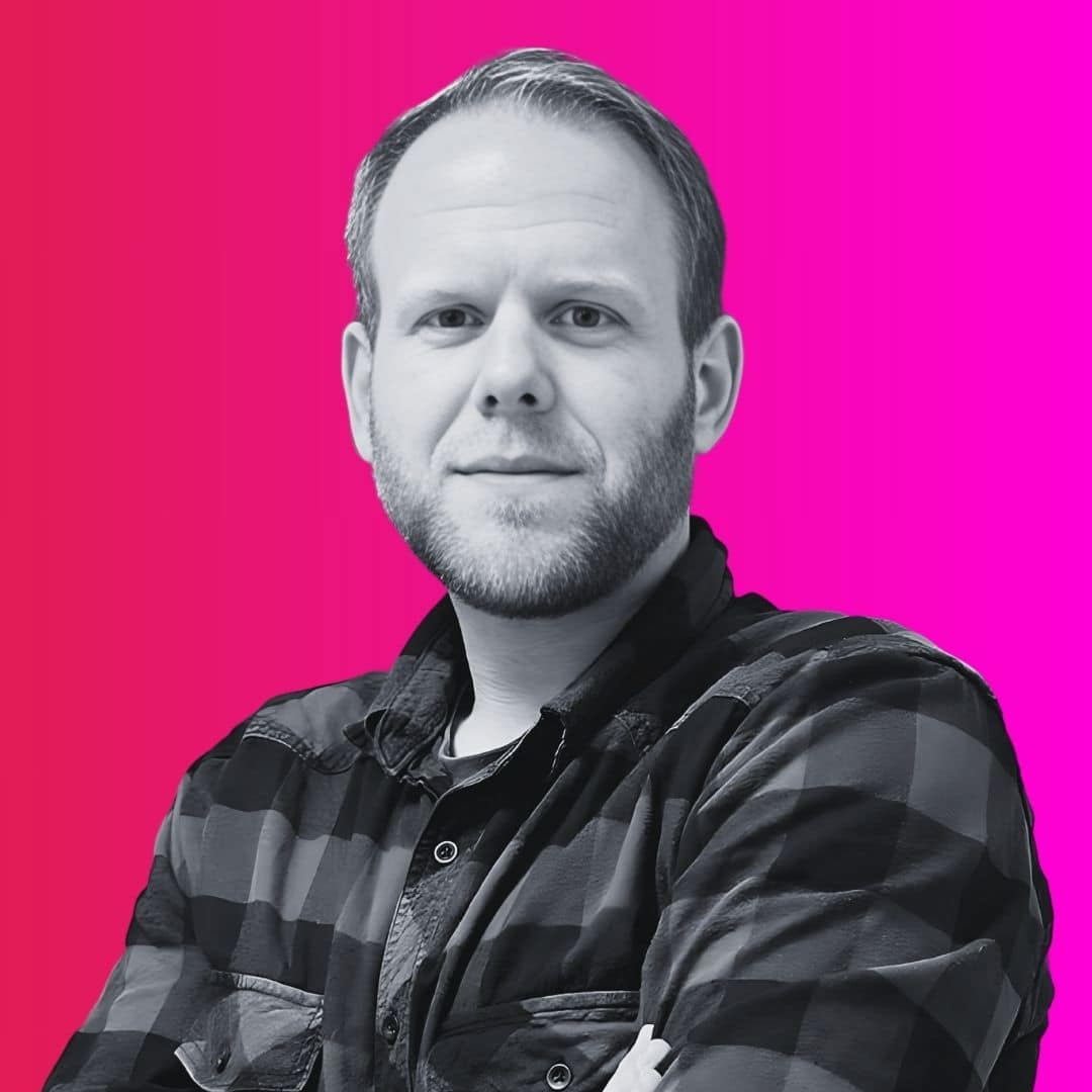 Mann vor pinkem Hintergrund posiert lächelnd